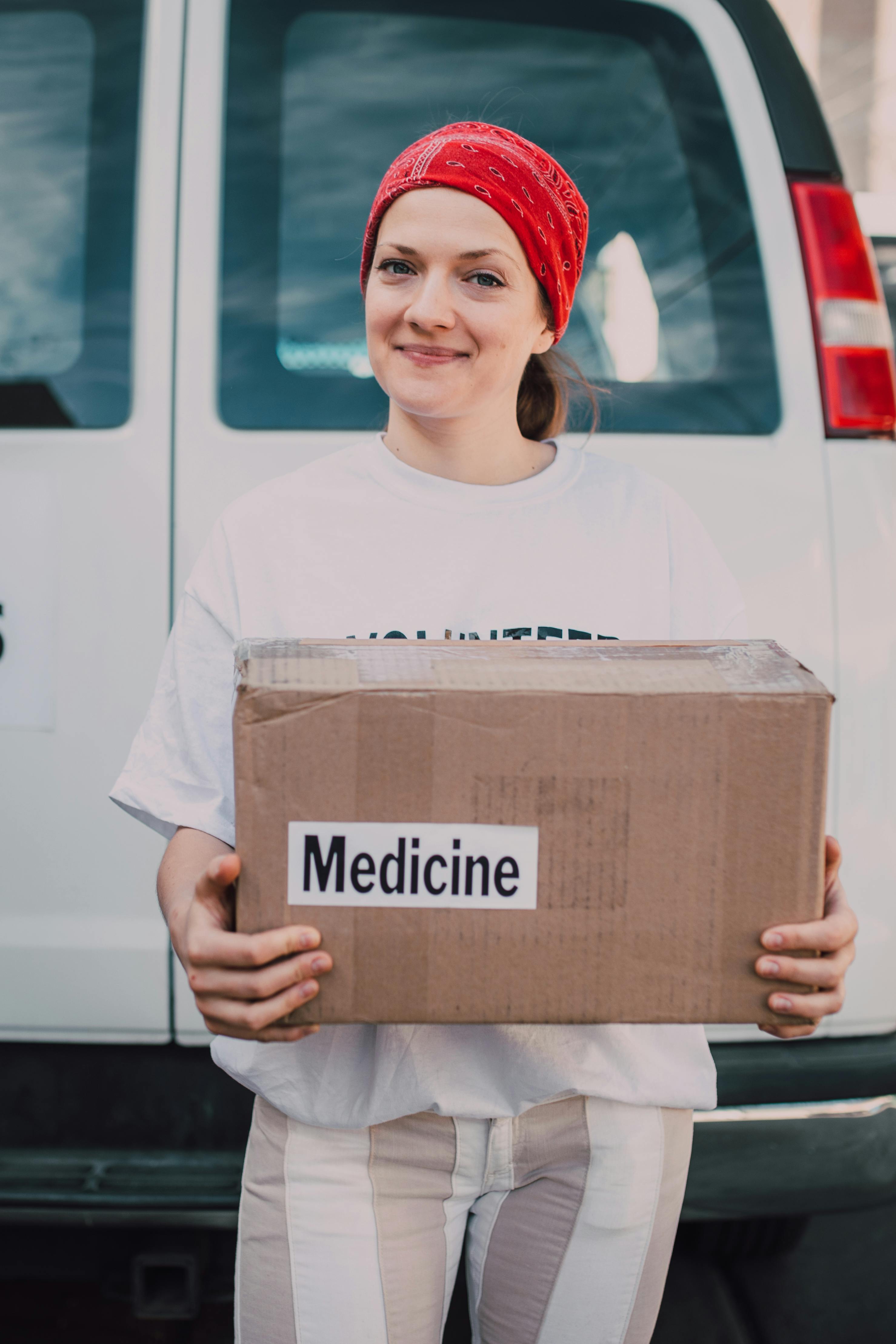 man in white crew neck t shirt holding brown cardboard box