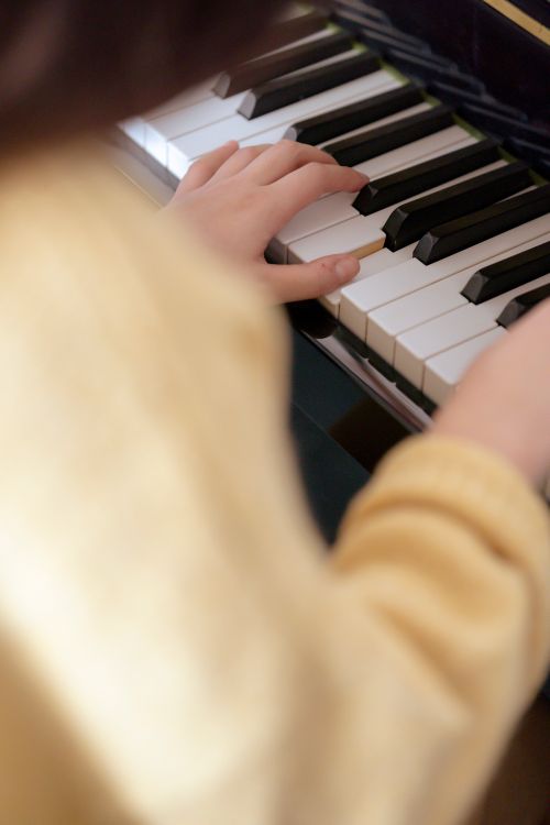 Free High angle of crop unrecognizable female musician in warm sweater practicing music on piano in bright room Stock Photo