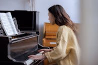 Woman playing on piano near music book in classroom