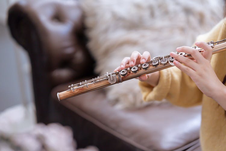 Unrecognizable Female Musician Playing On Flute On Couch At Home