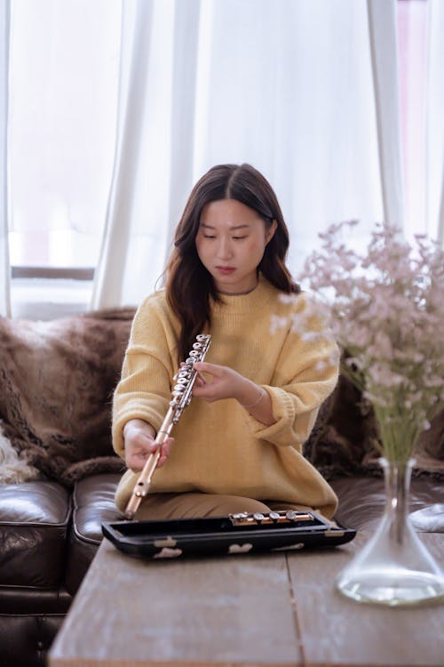 Asian lady with flute on couch near table in room