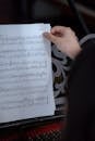 Anonymous woman turning page of music book near piano