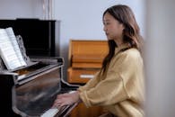 Ethnic female musician playing on piano in room