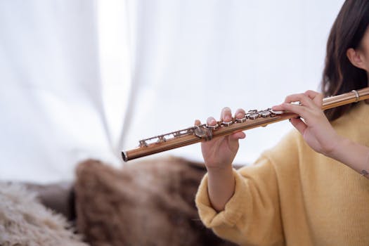 A woman practices flute playing indoors, capturing a serene musical moment.