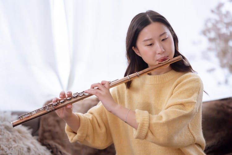 Asian Woman Playing Flute At Home