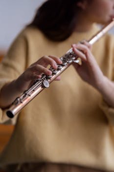 A woman artistically playing the flute indoors with a soft focus effect.