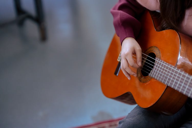 Unrecognizable Lady Playing Acoustic Guitar In Room