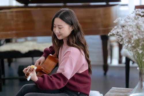 Smiling Asian woman playing guitar