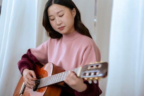 Skilled Asian guitarist performing song on guitar