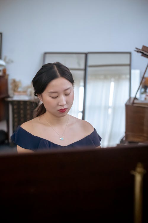 Concentrated Asian pianist rehearsing at home