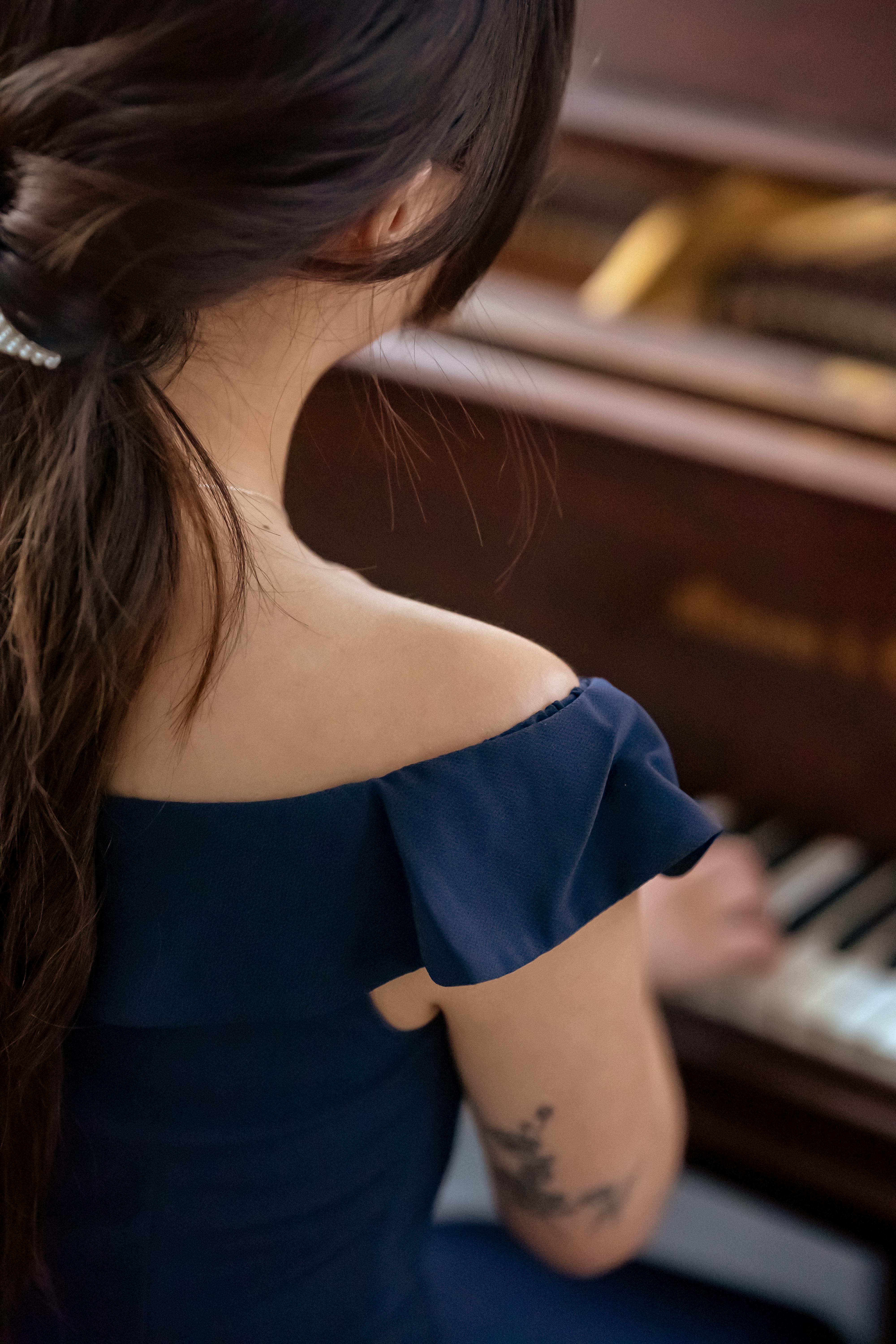 crop tattooed woman in dress playing piano