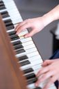 From above of anonymous female musician playing melody on keyboard of piano during music lesson in light room at home