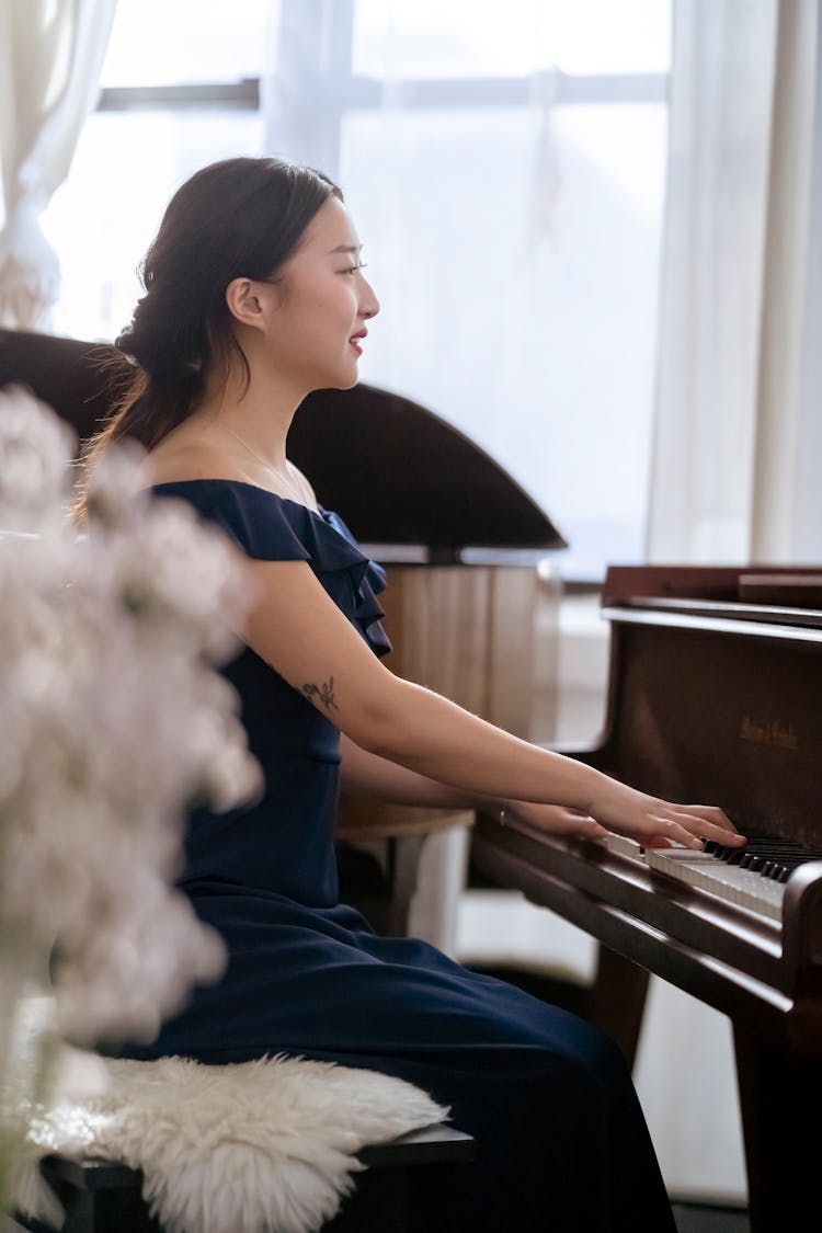 Elegant Asian Female Musician Playing Piano In Concert Hall