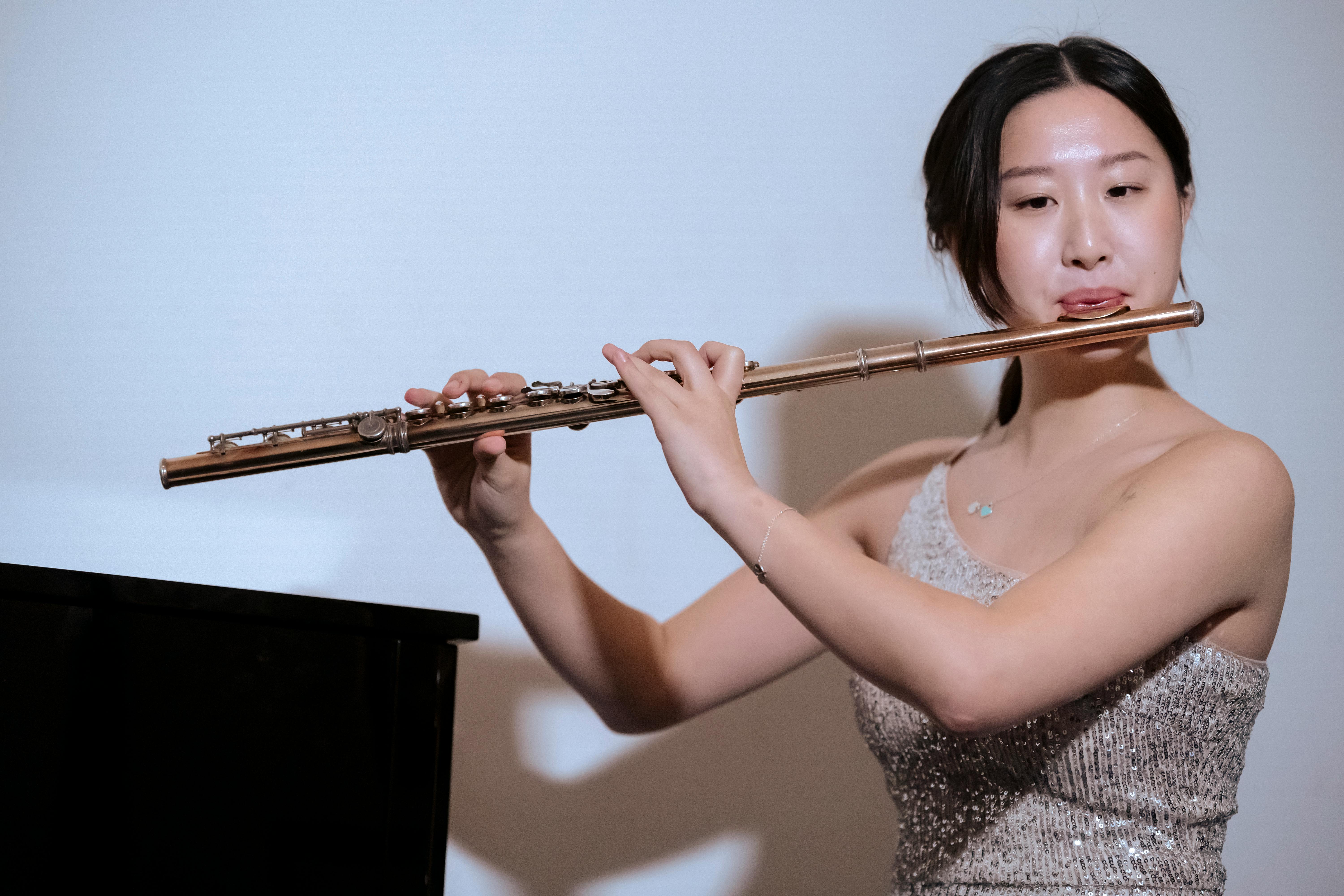 ethnic woman in dress playing flute at concert