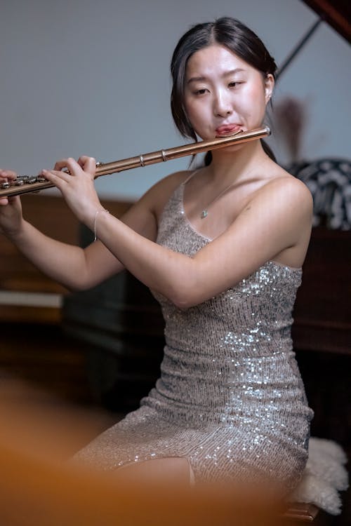 Asian woman playing flute near piano for event