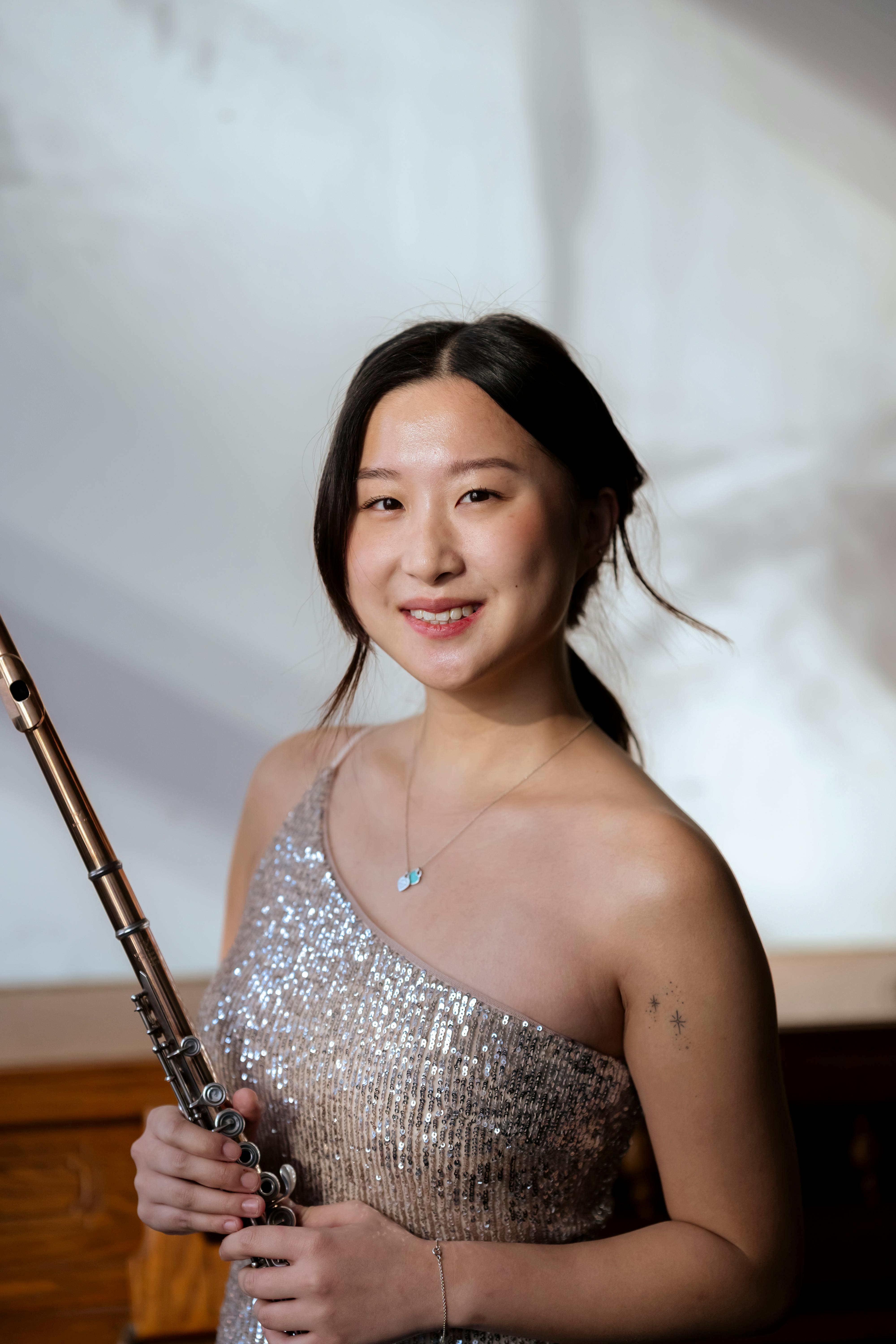 smiling asian woman in elegant dress standing with flute