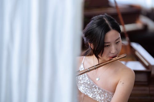 Asian woman playing flute during rehearsal in studio