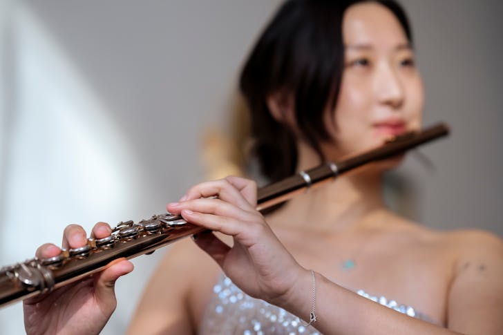 Asian woman playing flute at concert