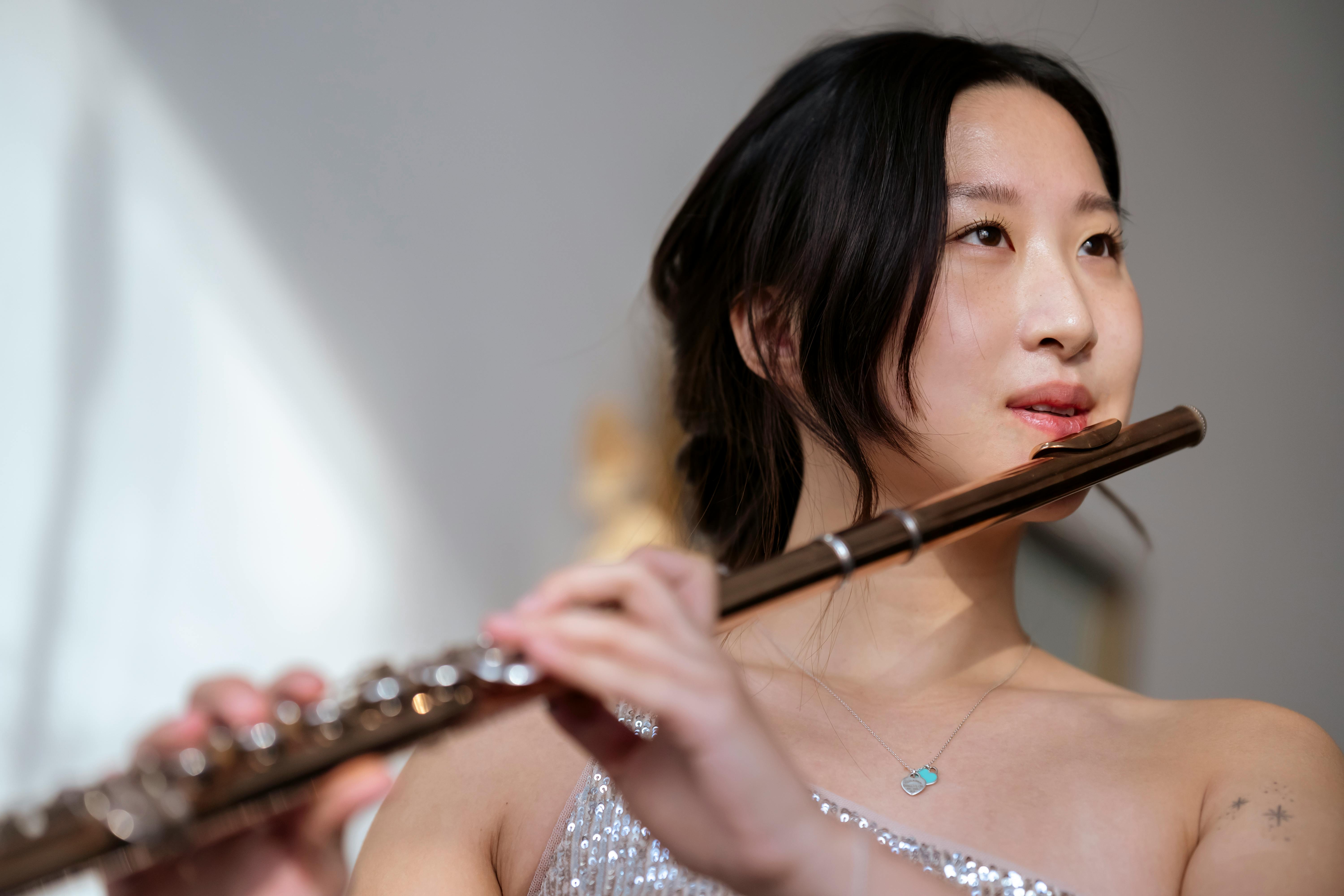 asian woman in elegant dress playing flute