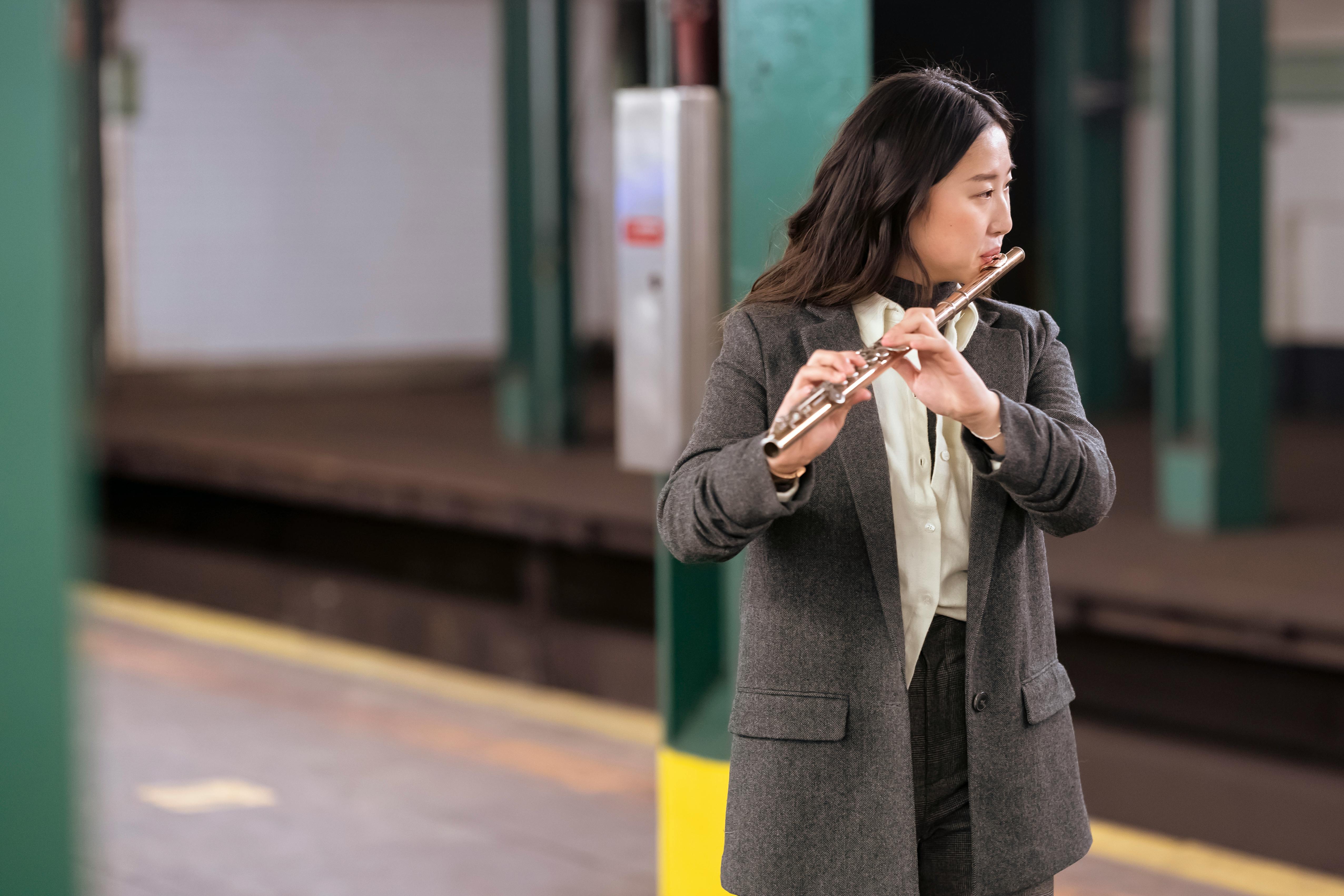 asian woman in suit playing flute in subway