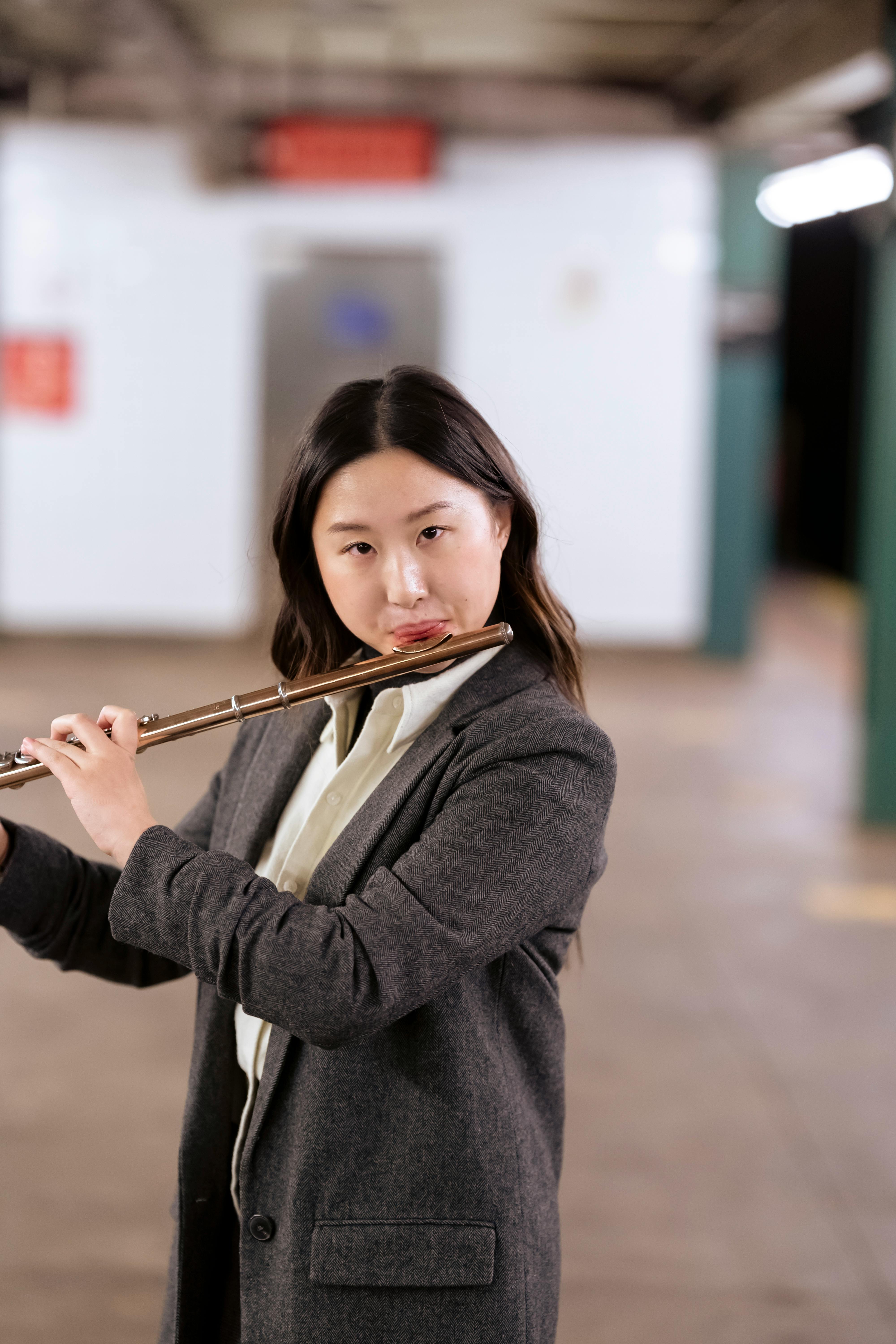 asian woman playing flute in city subway