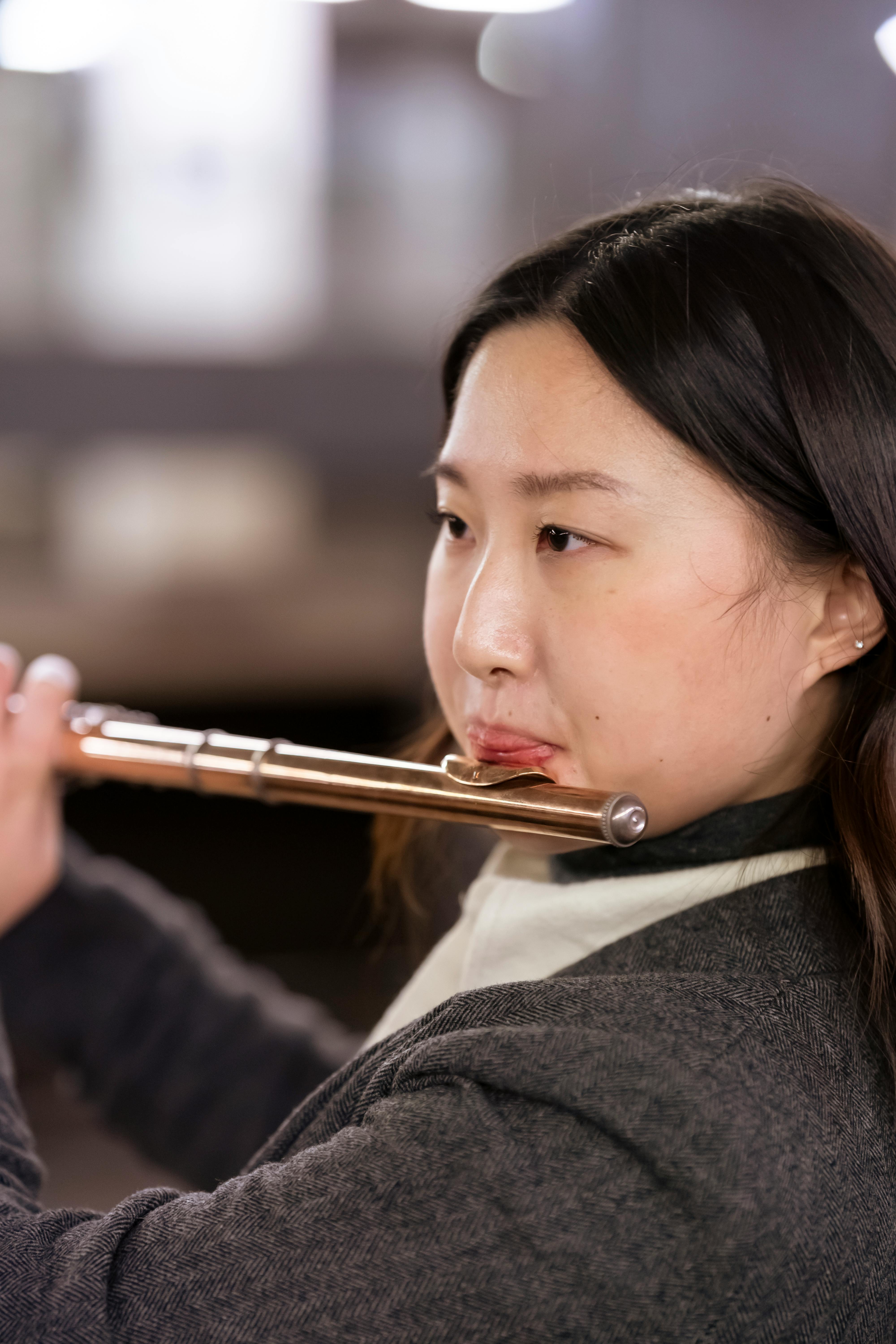 elegant asian woman in formal suit playing flute