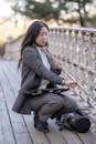 Asian woman with flute squatting on wooden bridge