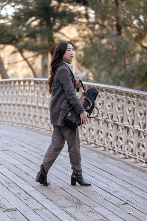Woman Wearing a Brown Blazer Walking on a Wooden Deck
