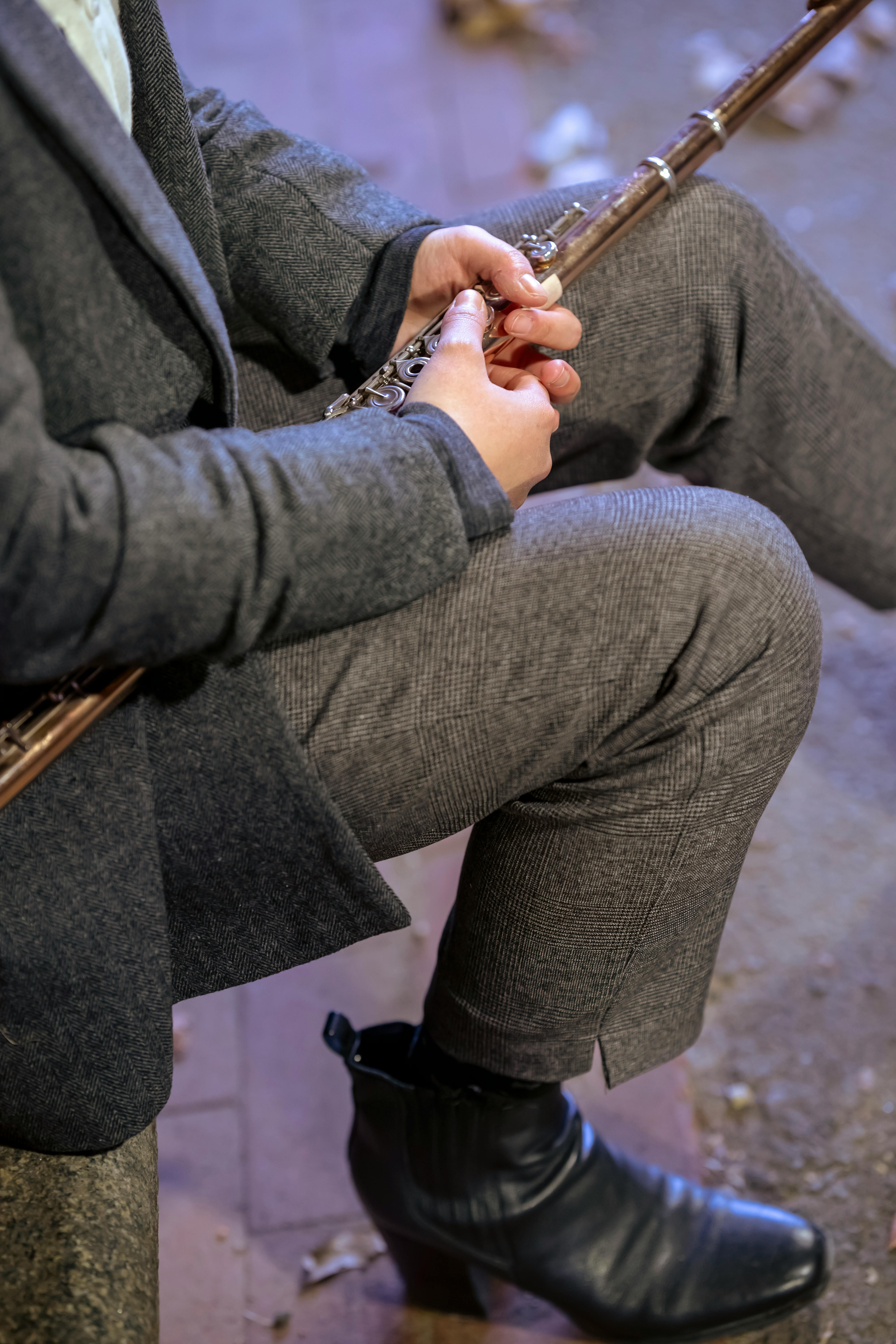 woman with flute wearing suit sitting on sidewalk