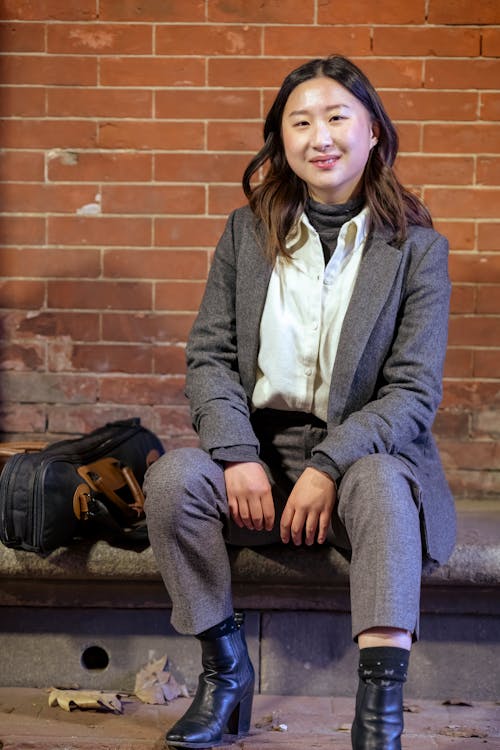 Positive ethnic woman sitting on stone border on street