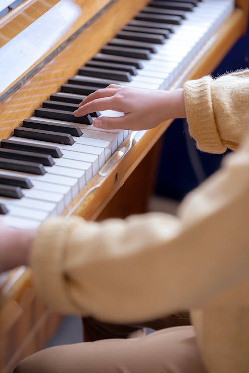 High angle of crop anonymous female musician practicing music on piano at daytime