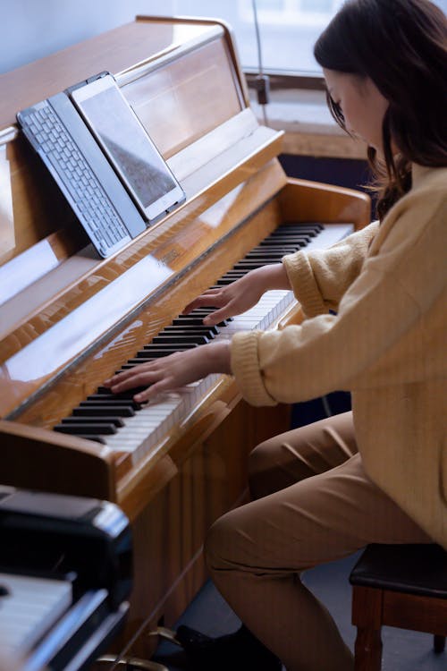 Asian musician playing piano and using tablet