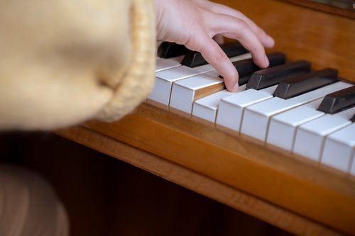 Free High angle of crop anonymous female pianist sitting at piano and pressing keys while practicing music Stock Photo