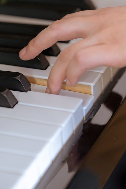 Closeup of crop unrecognizable female pianist gently playing piano during rehearsal of music perfomance