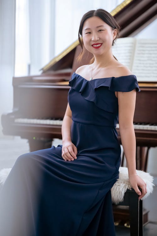Smiling Asian female sitting near piano in room