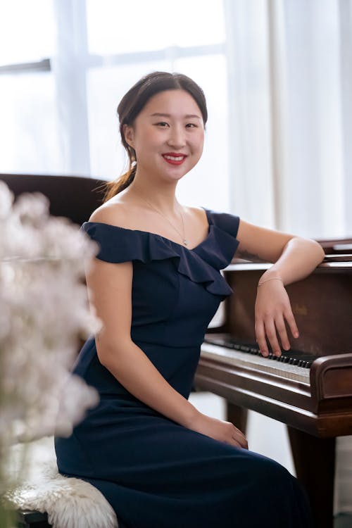 Happy Asian female sitting near piano in room