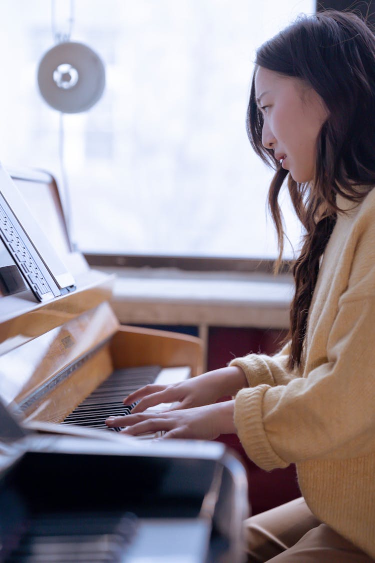 Concentrated Asian Woman Playing Piano In Studio