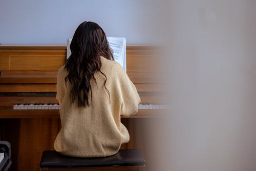 Free Anonymous female playing piano in room Stock Photo