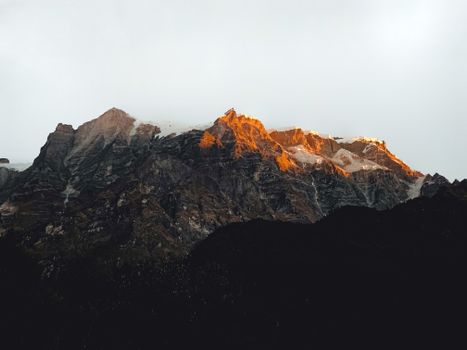 A breathtaking view of sunlit mountain peaks casting a warm glow at sunrise, highlighting rugged terrain.