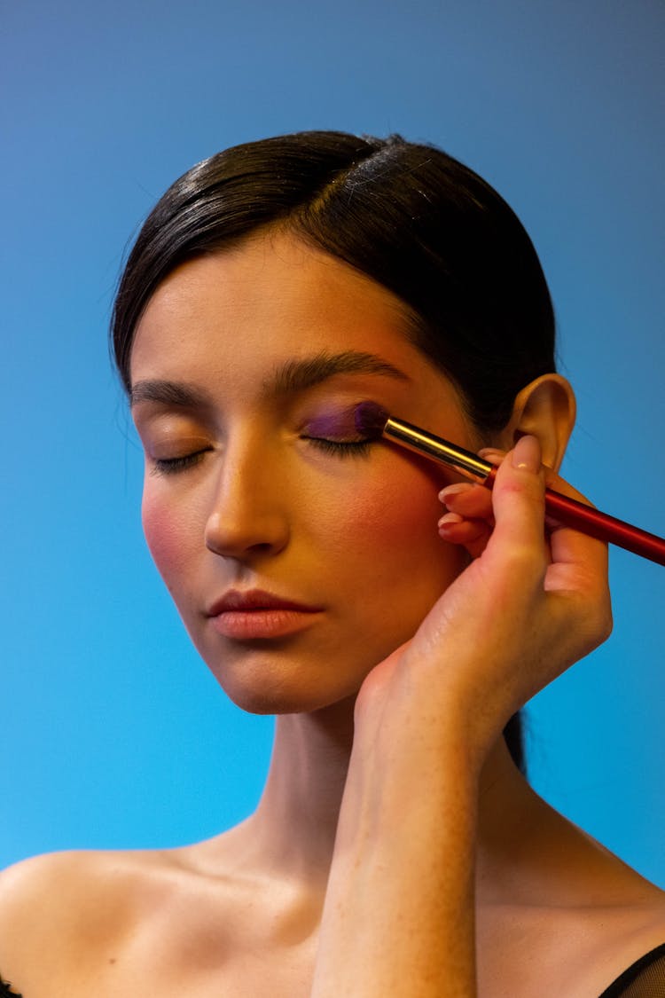 A Person Applying Eyeshadow Makeup To A Woman