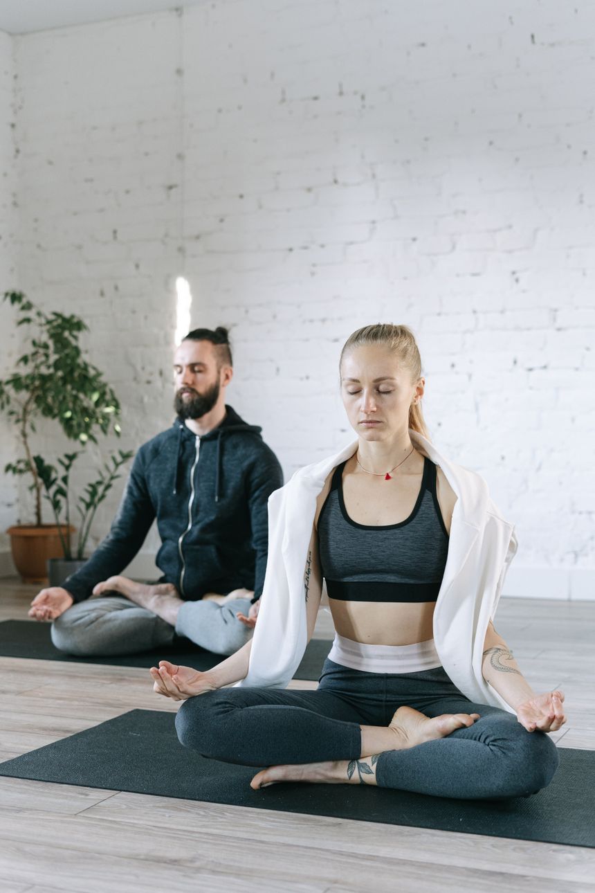 A woman and a man sitting cross-legged in a calm studio, mid-breathwork, photo by Ivan S on Pexels