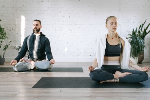 Couple meditating in lotus position in a serene room, enhancing mental peace.
