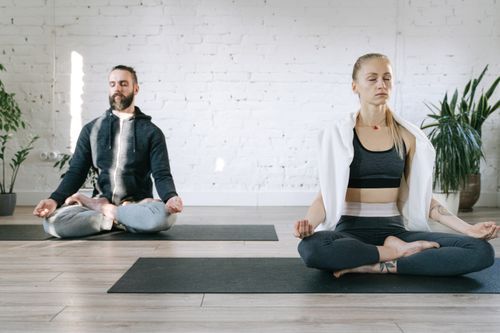 Free Couple meditating in lotus position in a serene room, enhancing mental peace. Stock Photo