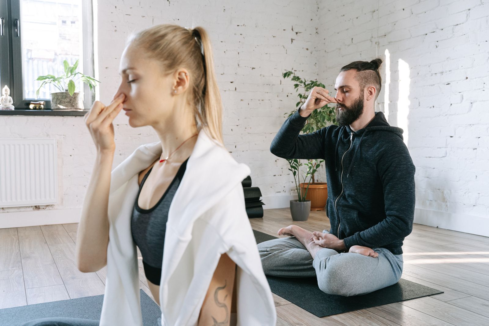 A man and woman practicing mindful yoga breathing exercises together in a serene indoor setting