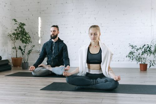 Free A man and woman meditate in a serene indoor space, promoting mindfulness and wellness. Stock Photo