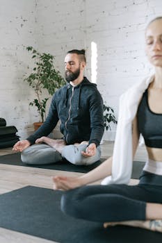 Serene indoor yoga practice with a man and woman in meditation pose.