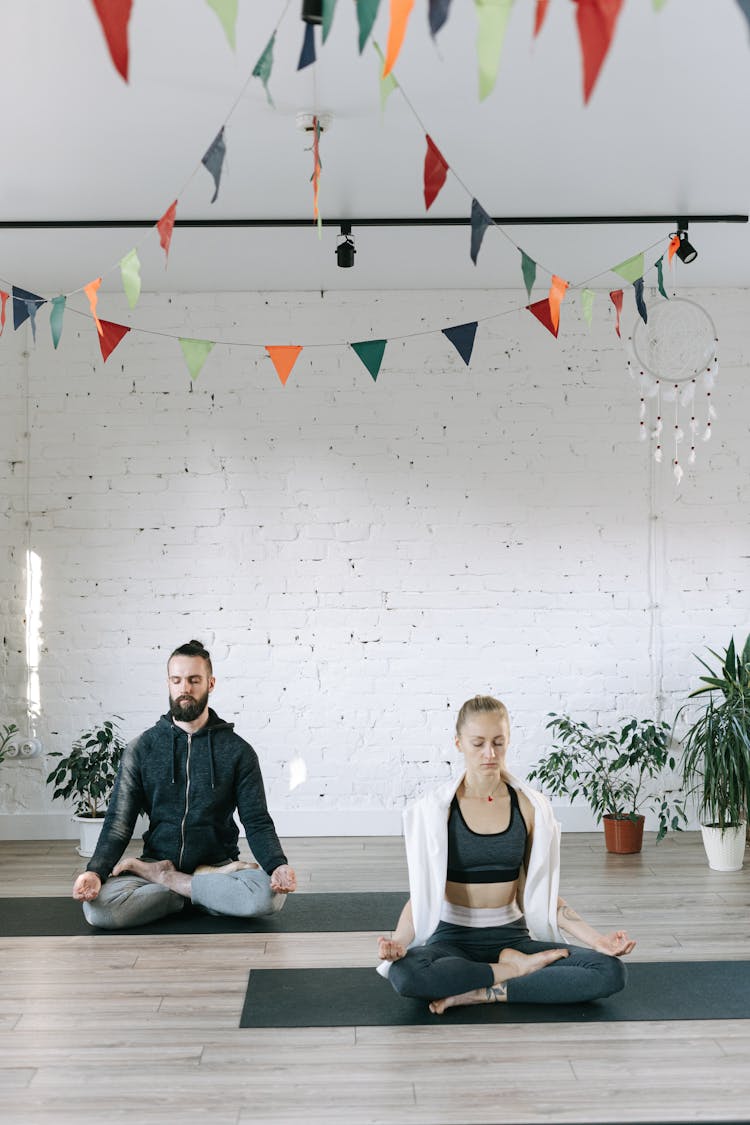 A Man And A Woman Meditating In Lotus Position