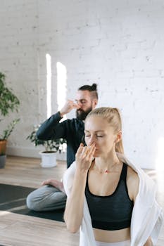 A man and woman meditating and practicing yoga breathing indoors.