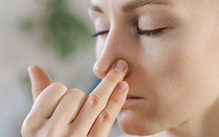 Close-up of a woman doing a breathing exercise with eyes closed indoors.