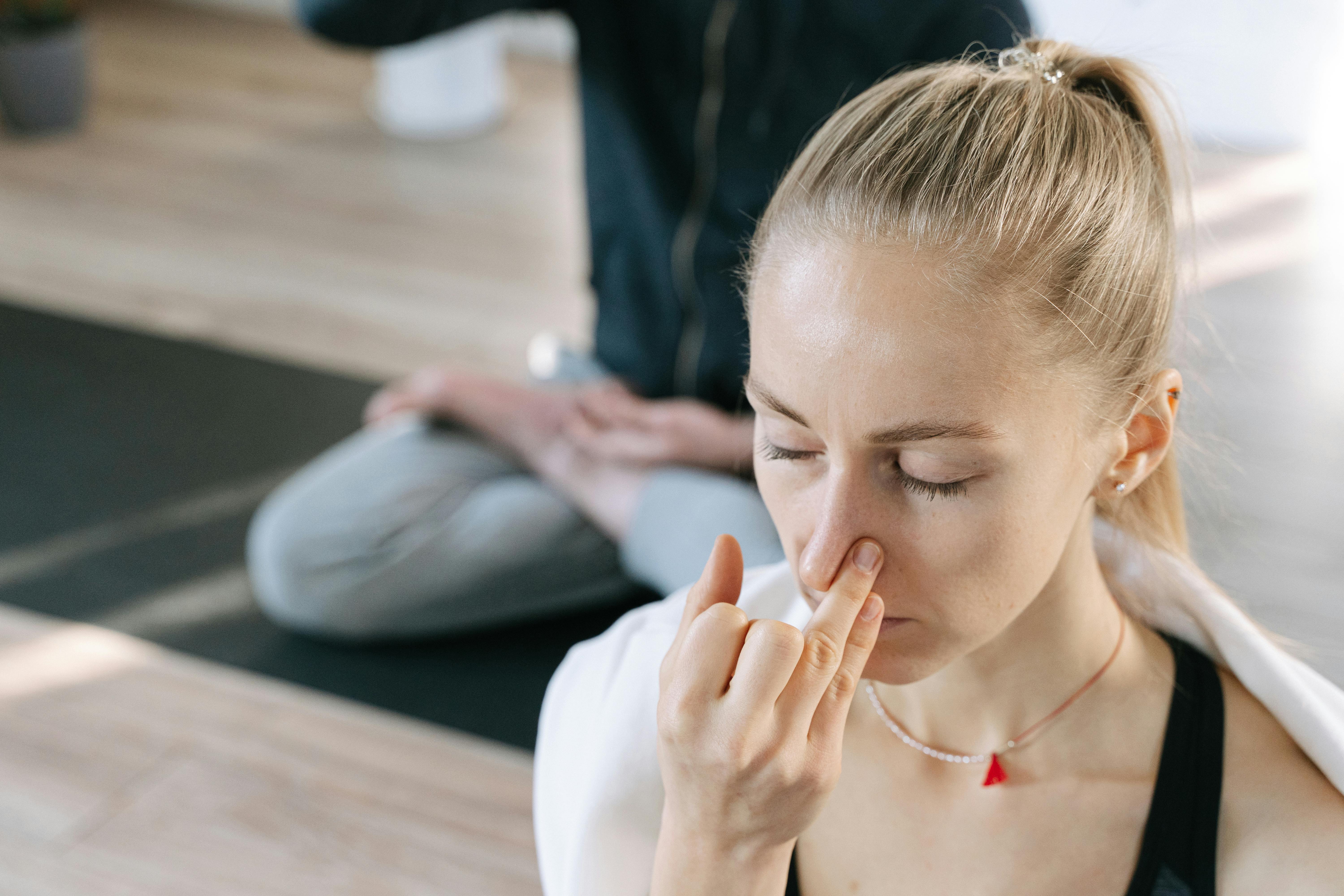 Woman meditating indoors practicing yoga breathing techniques with focused concentration.